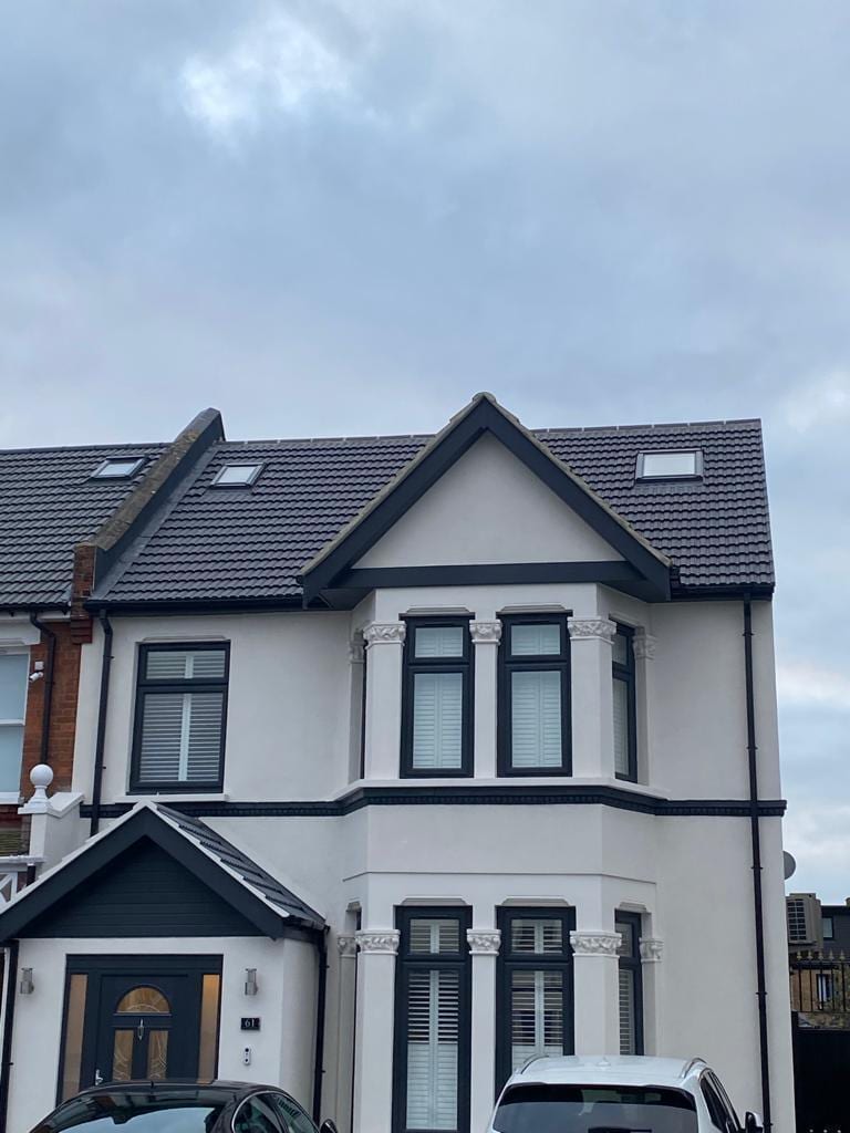 White smooth-rendered front elevation with bay window and black timber trim