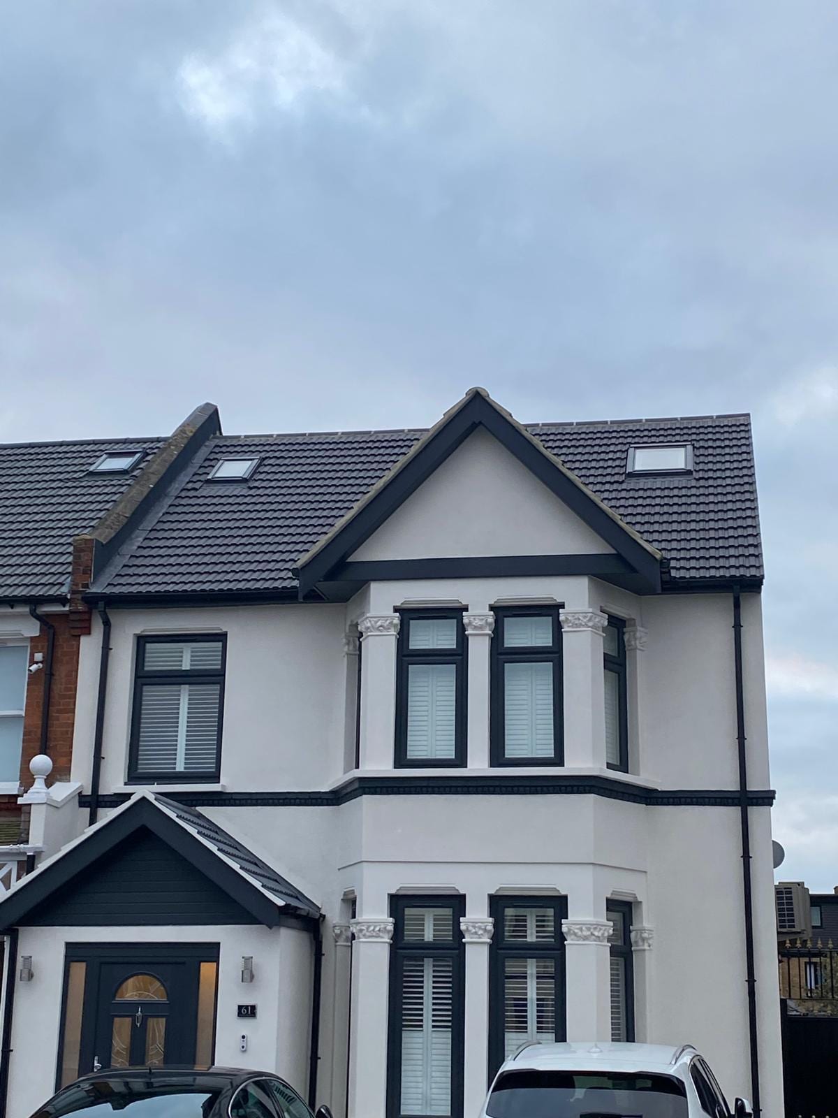 Smooth white render with bay window, stone corbels and dark gable trim