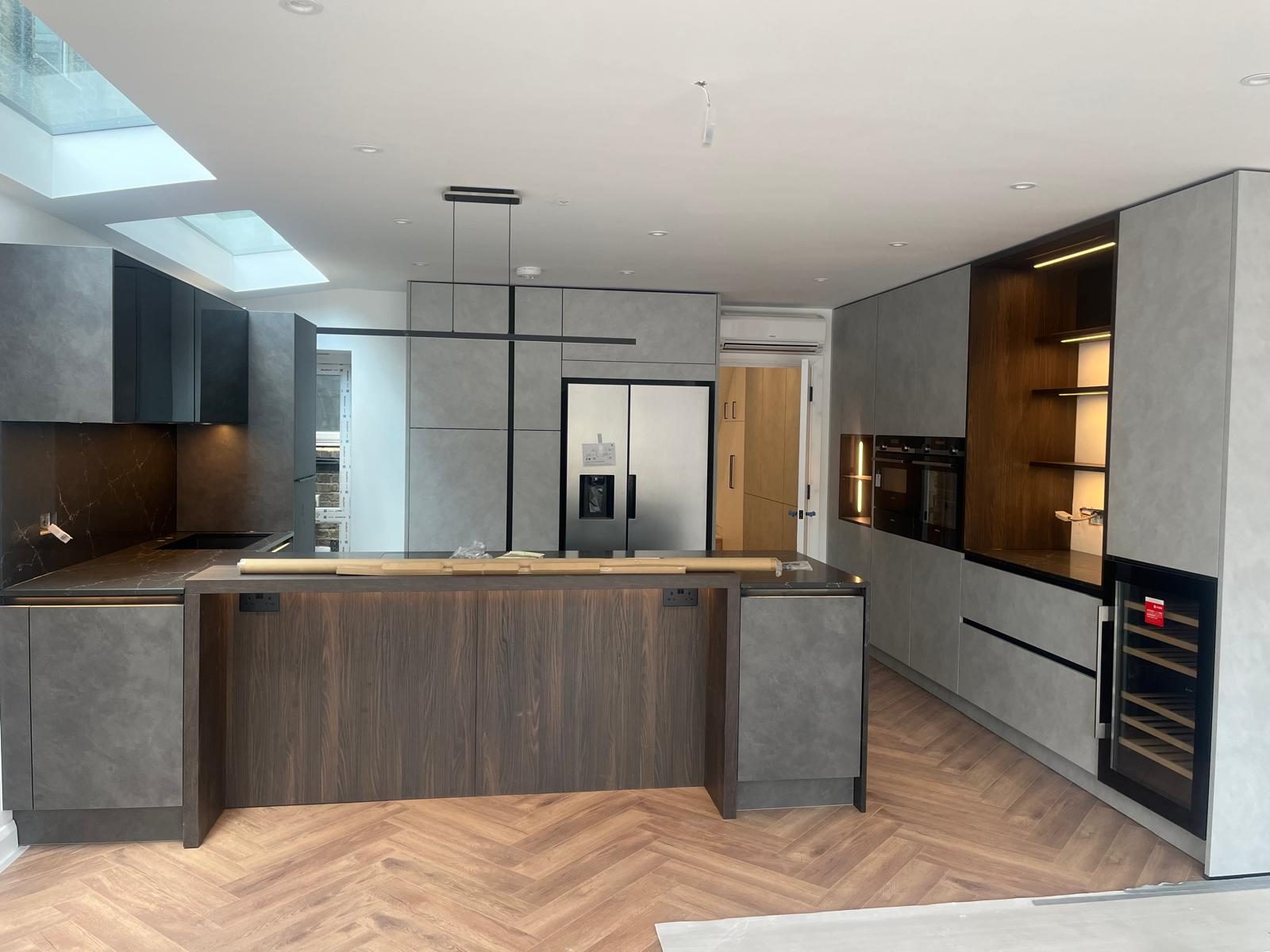 Open-plan grey and walnut kitchen with island and skylights